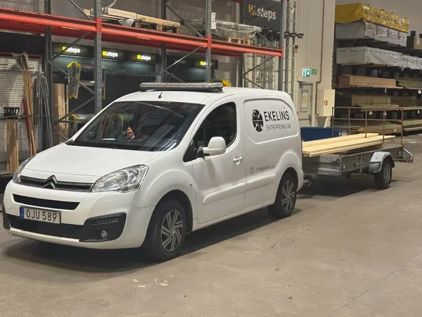 Bil med Ekelins Entrepenad ABs logotyp och släp med virke